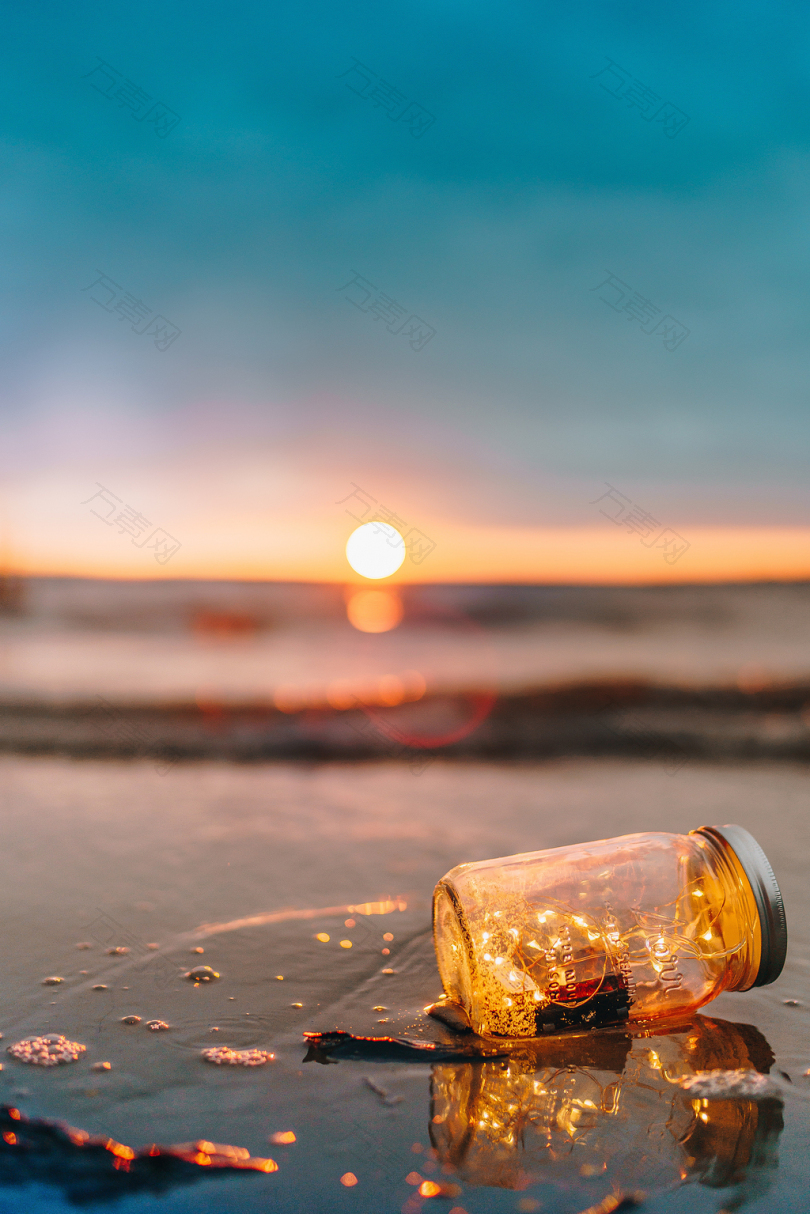日落时海滩上透明玻璃瓶