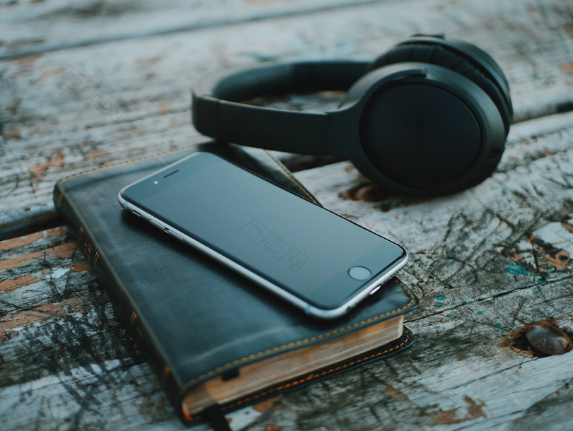 空间灰色iPhone6在书上靠近黑色无线耳机