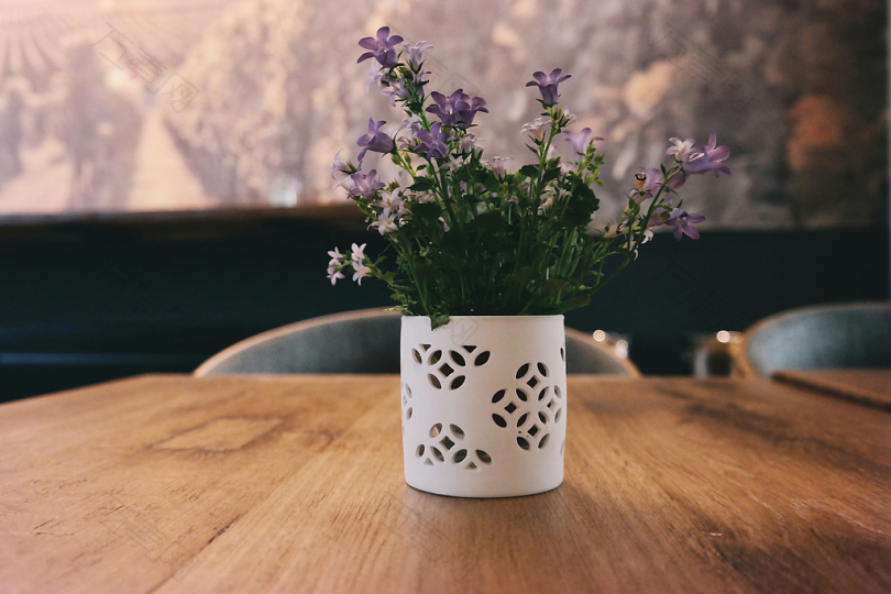 紫色的花瓣在白色的花瓶上放在棕色的木桌上