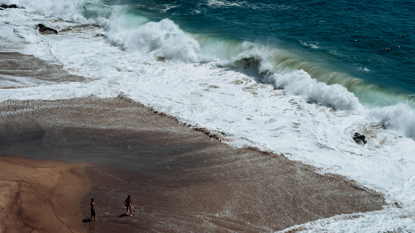 海岸上的两个人面对海浪