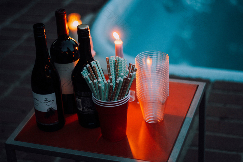 茶杯旁三酒瓶方红桌上蜡烛