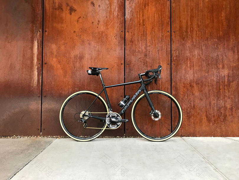 黑色公路自行车停在棕色木墙旁边
