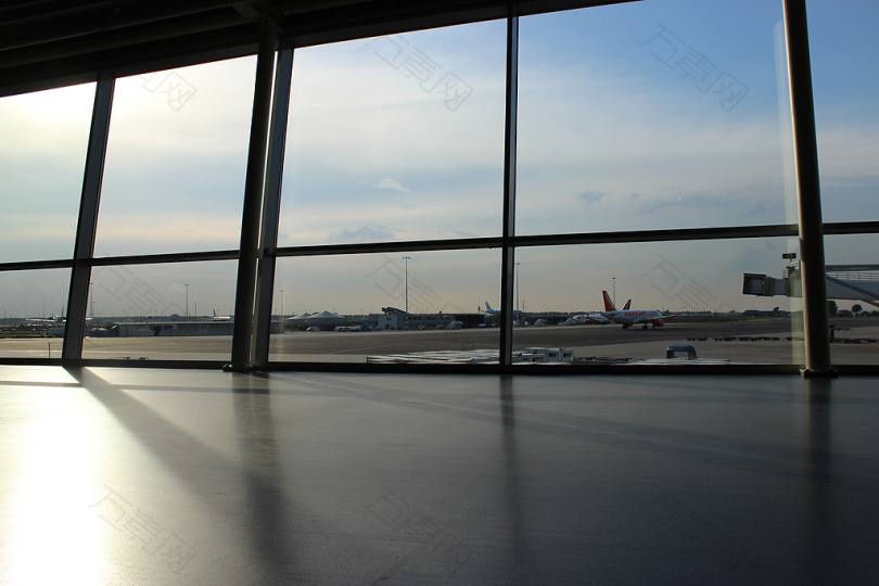 白天在蓝天下显示飞机和跑道的玻璃面板窗口
