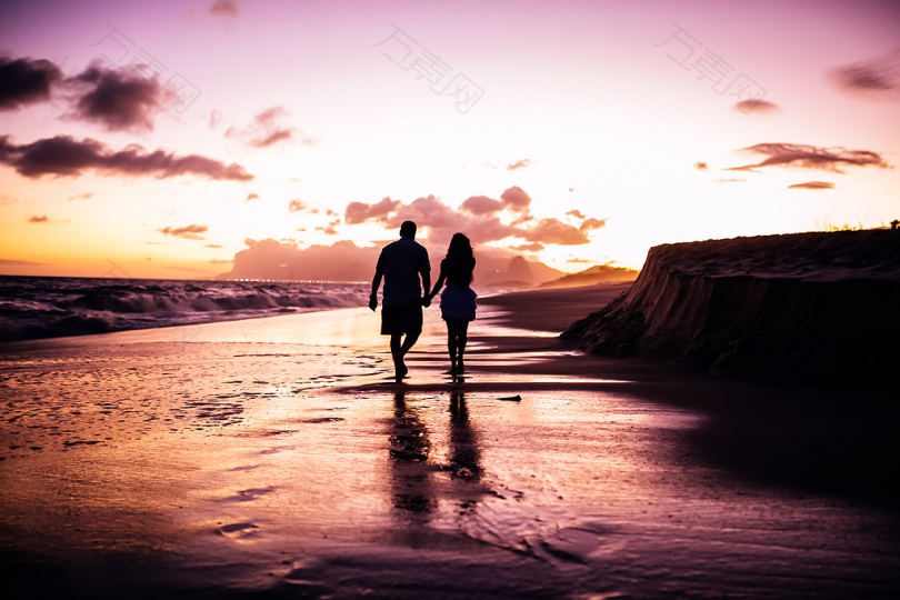 夕阳下情侣在海边散步
