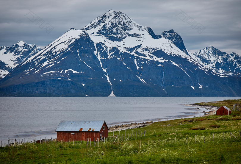 两个棕色的木屋在白天的水和雪山的蓝色身体附近的照片