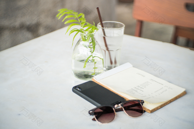 黑框太阳眼镜旁的黑盒智能手机和白封面白书