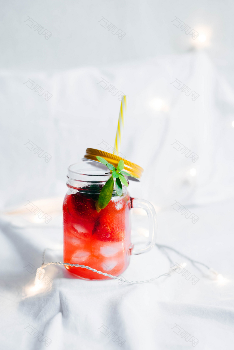 清澈的玻璃梅森杯草莓饮料白色的纺织物被弦灯包围
