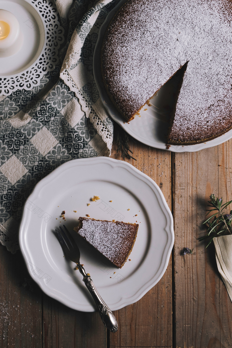 棕色餐桌上有圆形蛋糕和叉子的圆形白色陶瓷板