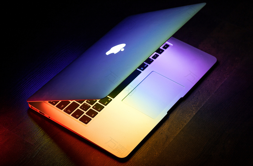 木制表面上彩虹色点亮的MacBook