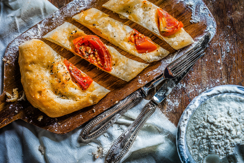 西红柿木板面包在勺子和餐刀旁边的照片