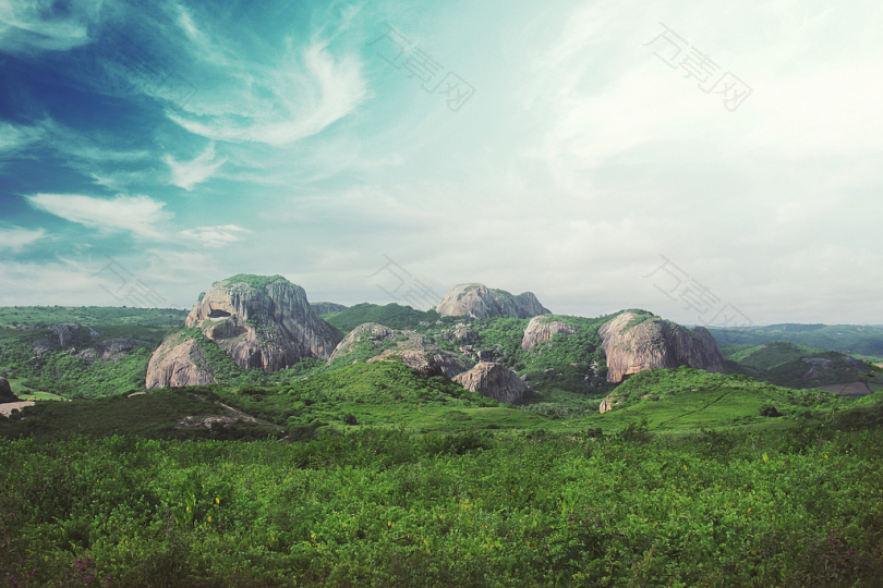蓝天下的绿野环绕的岩石