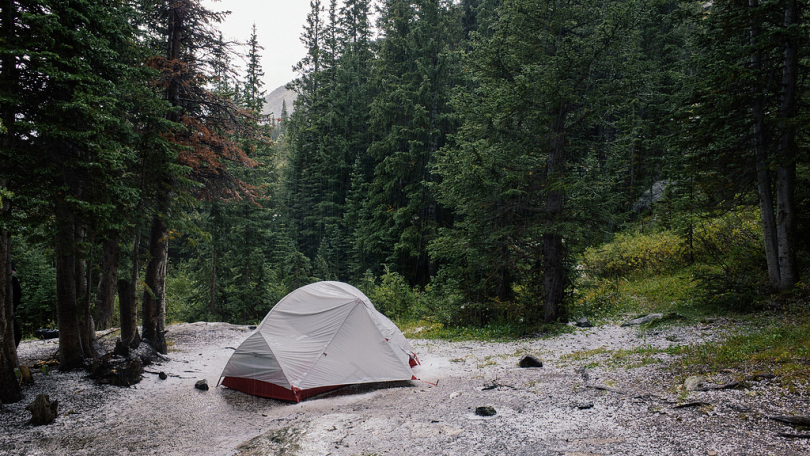 树木环绕的湖旁的灰色帐篷
