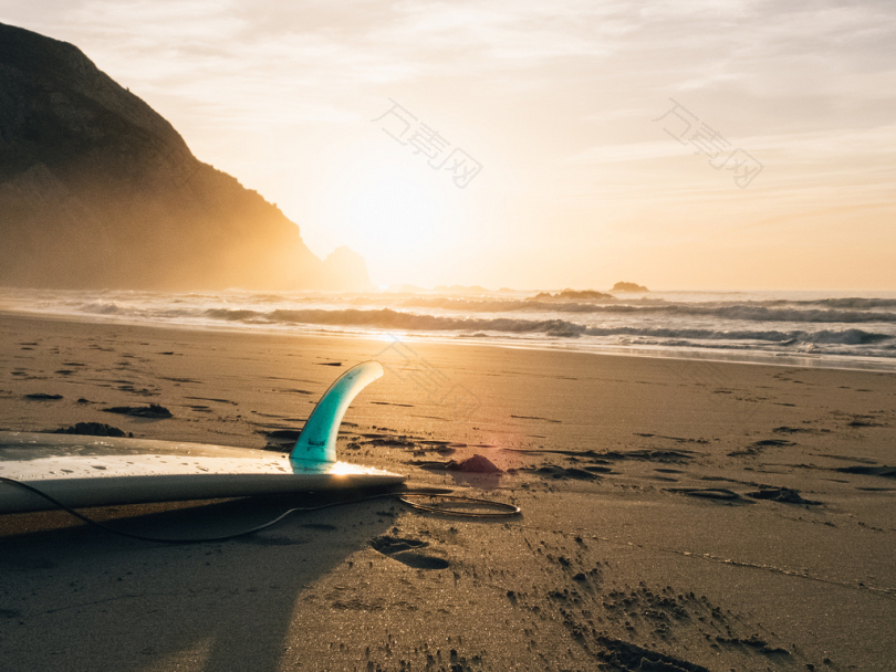 夕阳下海边褐沙冲浪板