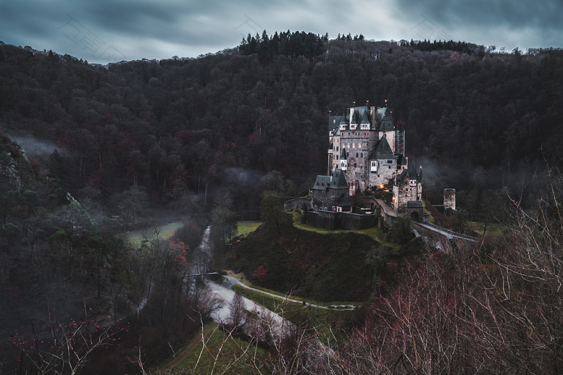 灰色的混凝土城堡在灰色的天空下被树木环绕