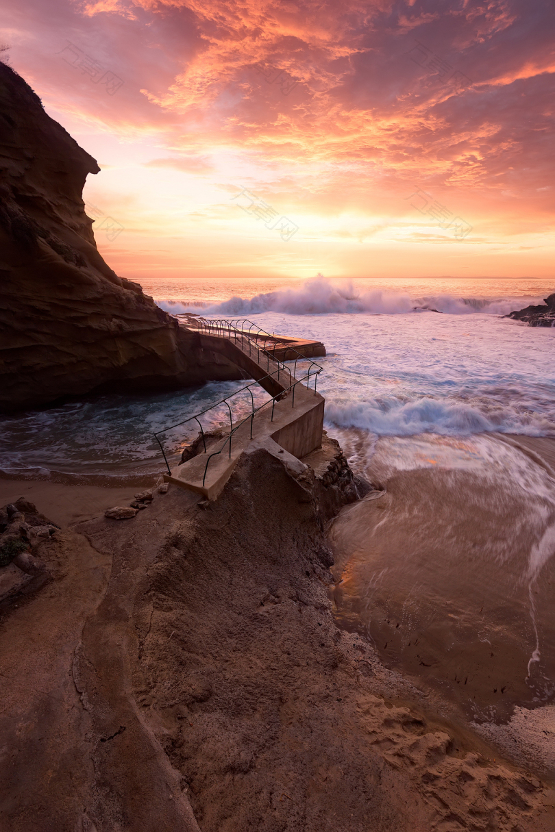 日落时岩石海岸的波浪撞击
