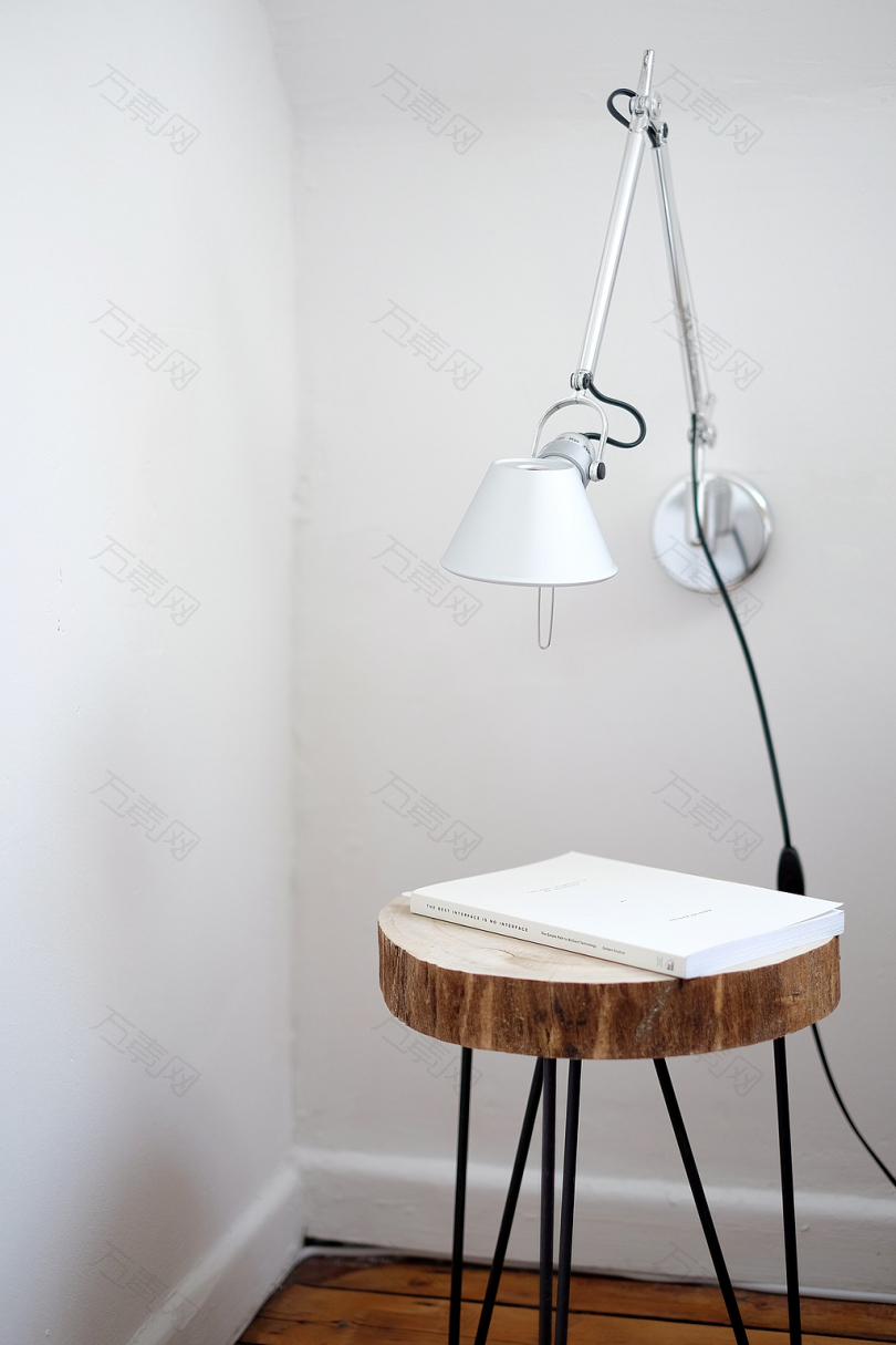 灰色的台灯安装在白墙下的棕色凳子上白色的书在墙角顶上