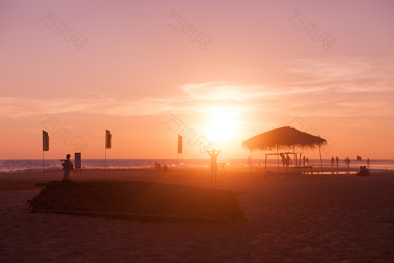 夕阳傍晚海边的剪影海滩小屋