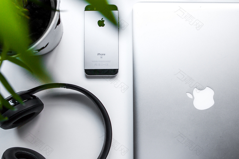 空间灰色iPhone手机旁边的耳机和银色MacBook