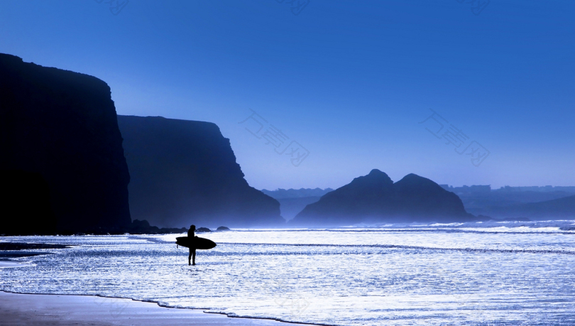 蓝色时辰站在海边的冲浪板的剪影