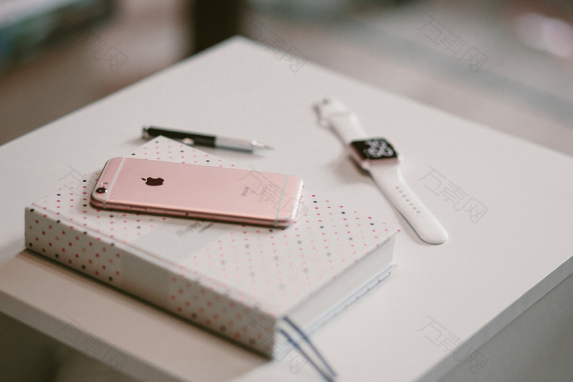 玫瑰金iPhone6S在苹果手表附近的书