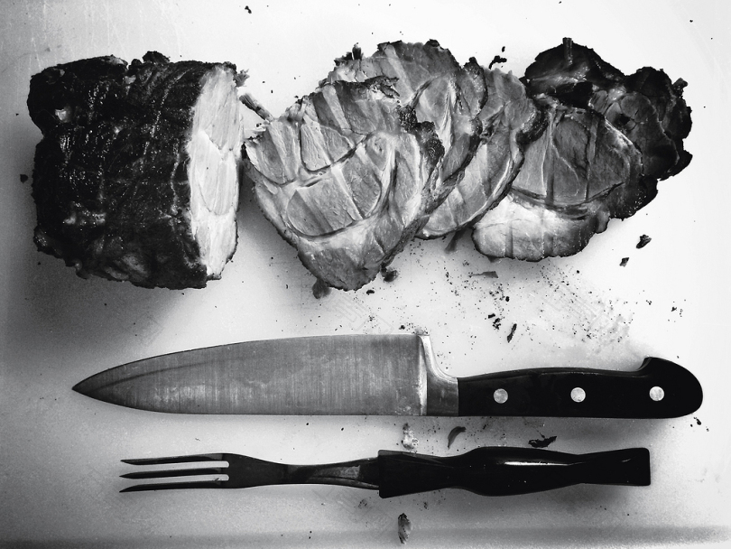 刀叉旁烤肉的灰阶照片