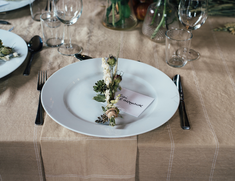 桌上白板和餐具上的绿色和白色装饰花