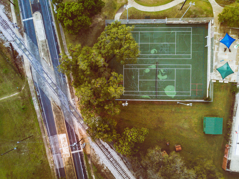 绿树草地网球场近树路铁路的高角度照片