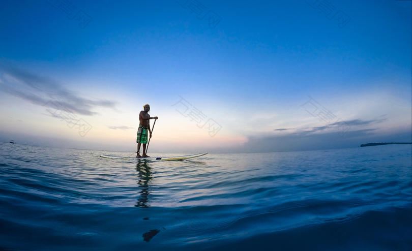 站在白色划桨板上的人在蓝天下把持着水上的桨