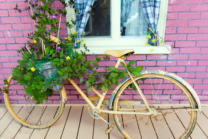 白天在红砖建筑附近有鲜花的棕色城市自行车