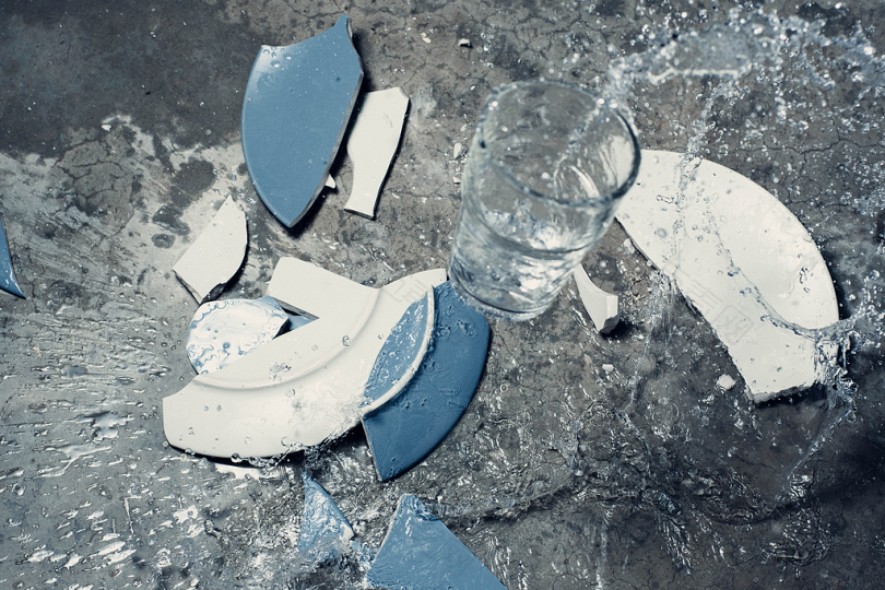 破碎的白色和蓝色陶瓷板和透明的饮用水玻璃