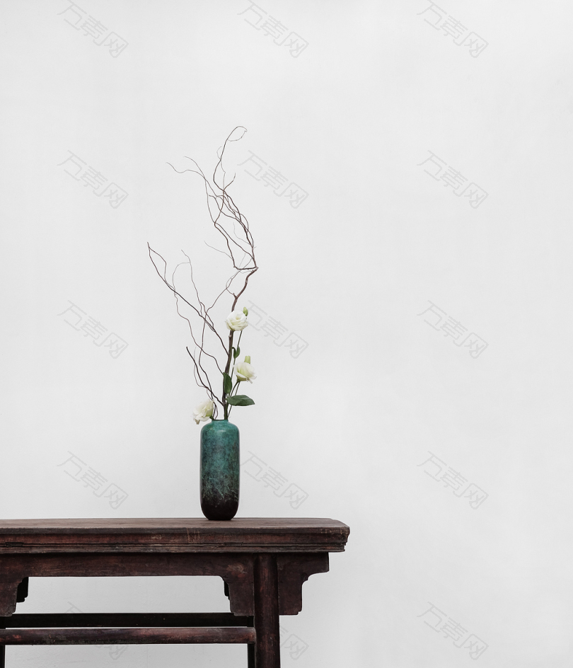 白色的绿色陶瓷花瓶在棕色木桌旁