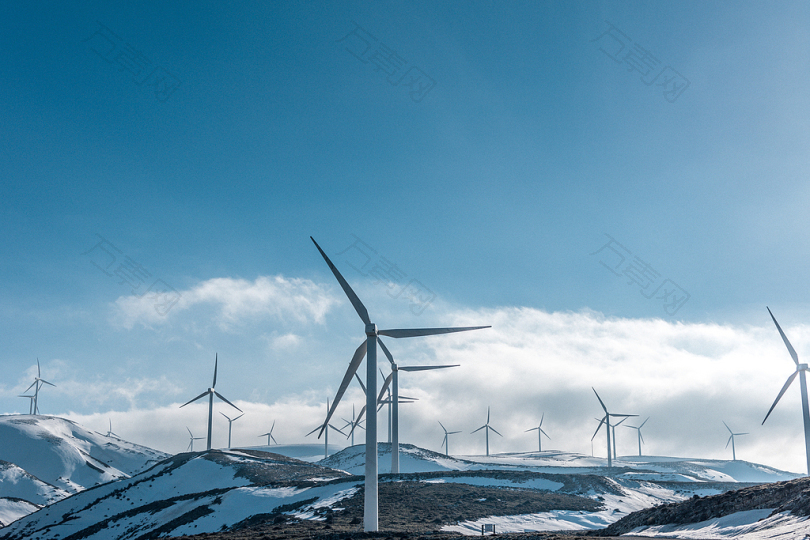 天晴蓝天下雪山上的风力涡轮机