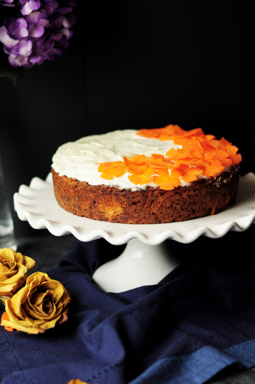 白色和橙色糖霜蛋糕在扇贝边白色陶瓷蛋糕架上