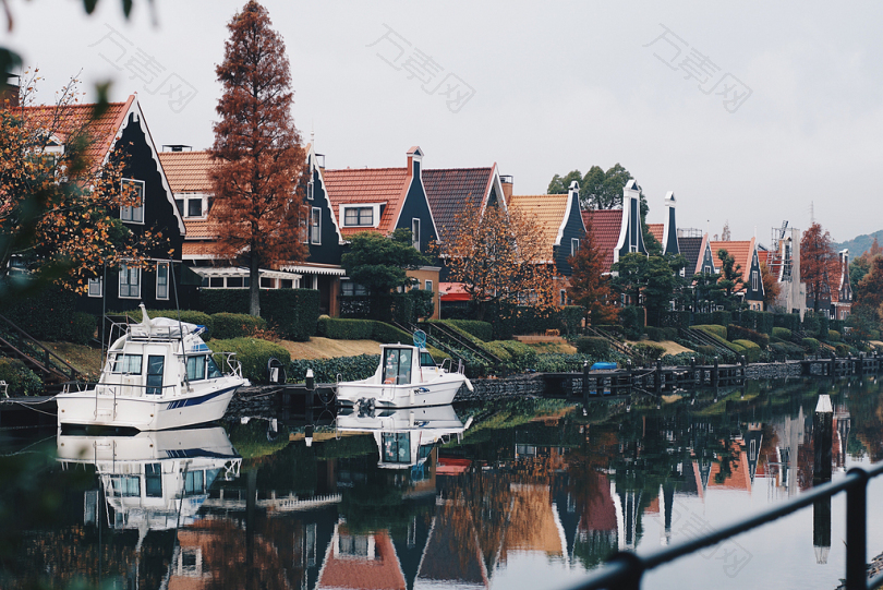 白天在棕色房子附近的河上有两条白色的小船