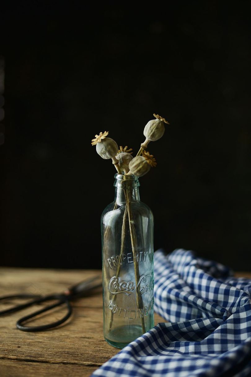 桌子上有白色花朵的透明玻璃瓶