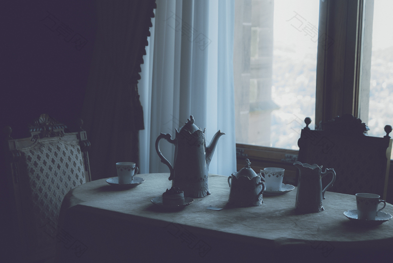 白色陶瓷茶具设置在靠近窗户的白色餐桌上
