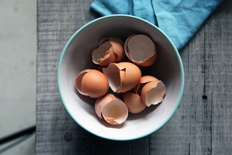 棕色蛋壳在圆形白色陶瓷碗上的灰色木板顶视图摄影