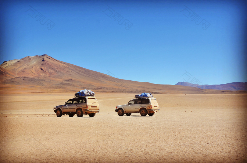 灰色沙漠中的两辆灰色越野车