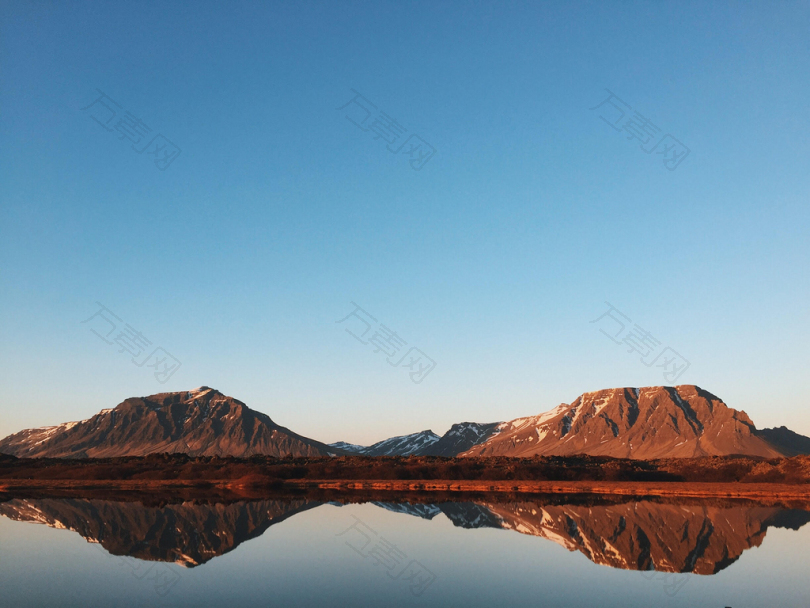 平静的湖面反射岩石悬崖和晴朗的蓝天
