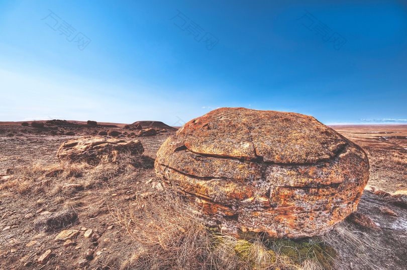 白天蓝天下荒原上的褐色岩石