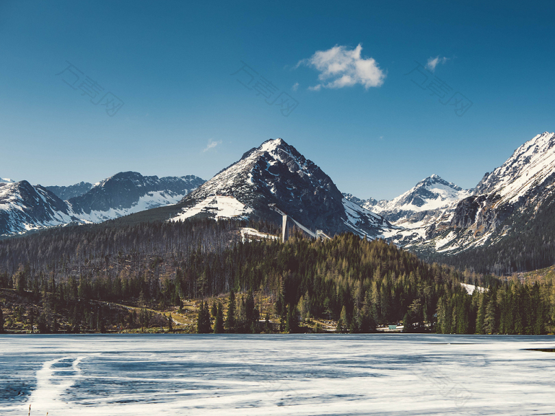白天树木覆盖的冰雪覆盖的山脉和冰冻的湖泊